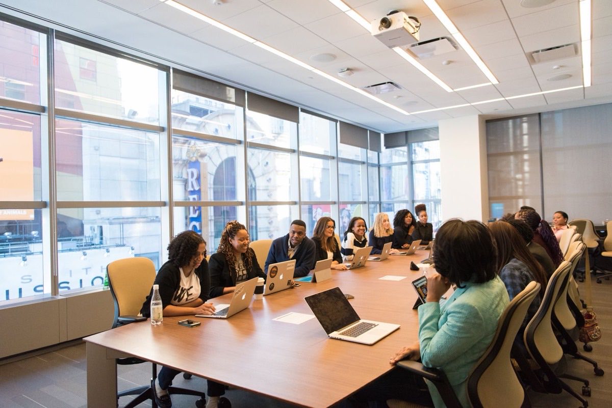 A leadership meeting around a long conference table in a bright boardroom